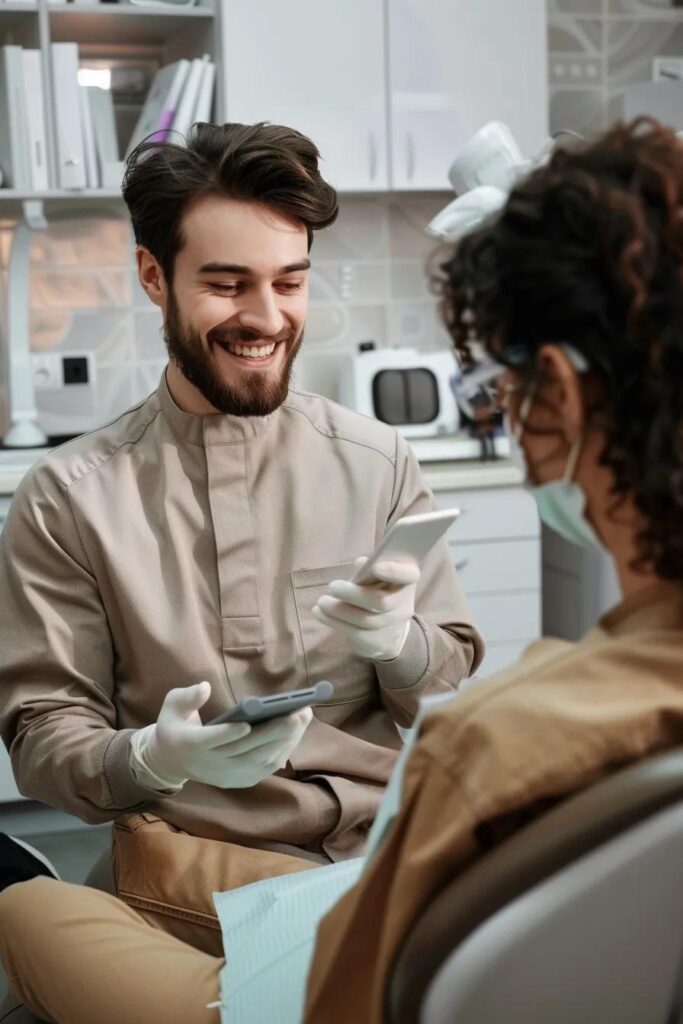 Dentist engaging with a patient, discussing treatment options using a smartphone in a modern dental clinic setting.