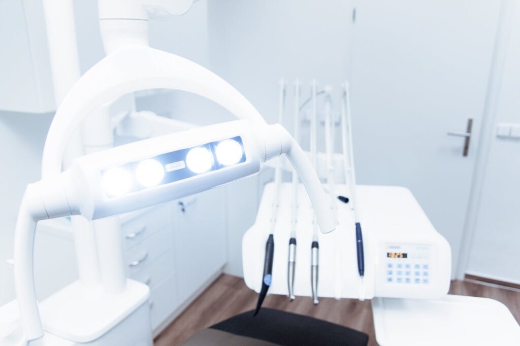 Dental examination room with bright overhead light, dental tools, and modern equipment, emphasizing healthcare practice environment and patient care.